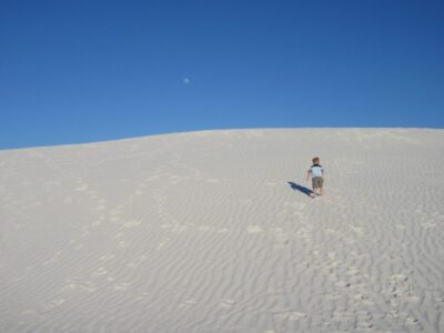 child climbs large sand dune at White Sands National Monument in New Mexico