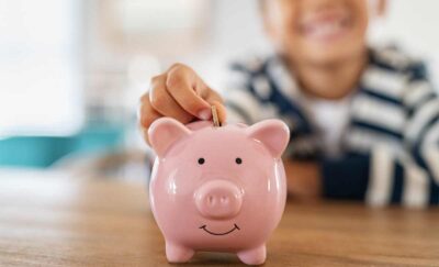 Photo of child adding a coin to a piggy bank